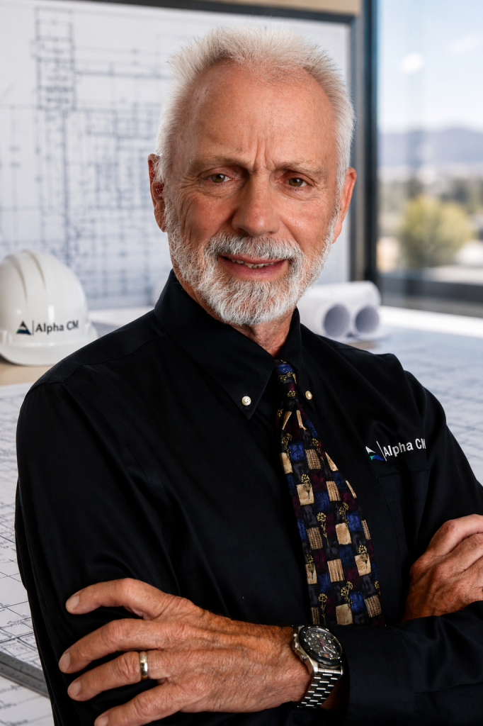A portrait of Brian Danley wearing a black shirt and a blue and beige patterned tie